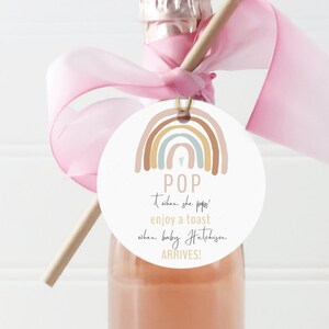Puede incluir: Una etiqueta de favor de baby shower imprimible con un diseño de arcoíris y el texto "POP when she poppi enjoy a toast when baby Hateliyon ARRIVES!"