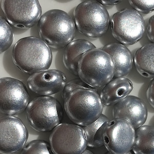 May include: A collection of silver-colored round beads with a smooth, shiny finish. The beads have two holes each.