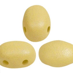 Op de afbeelding: Drie lichtgele, getextureerde kralen. Twee ovale kralen met twee gaten en één ei-vormige kraal met twee gaten. De kralen zijn op een witte achtergrond geplaatst. Het logo "Les perles par Puca PARIS" staat linksonder.