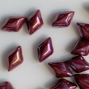 May include: A collection of maroon iridescent glass beads in a diamond shape.