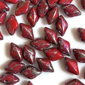 May include: A scattering of red and silver diamond-shaped glass beads. The beads have a mottled, marbled effect.