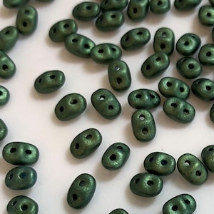 May include: A collection of small, dark green, oval-shaped beads with a matte finish. The beads have two holes in each.