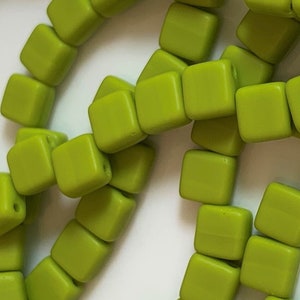May include: A strand of lime green square beads. The beads are made of a smooth, matte material and are strung together on a clear thread.