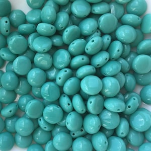 May include: A large pile of turquoise blue glass beads. The beads are round and have two holes in them.