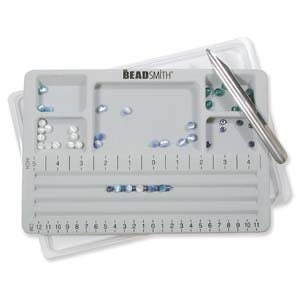 May include: Gray beading tray with compartments for sorting beads. The tray has a ruler and two grooves for stringing beads. The tray also includes a metal tool for picking up beads.