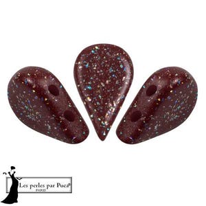 May include: Three maroon-colored, teardrop-shaped beads with iridescent glitter. Each bead has two holes for stringing. The beads are arranged in a fan shape against a white background. The beads are from Les perles par Puca Paris.