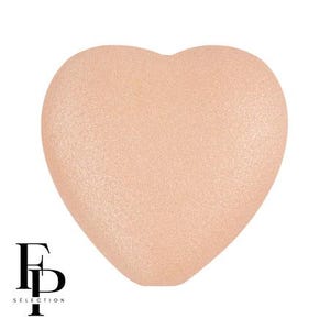 May include: A heart-shaped makeup sponge in a light peach color. The sponge has a textured surface and is set against a white background. The logo "FD SELECTION" is in black at the bottom left.