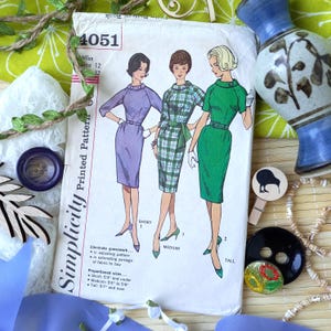 Peut inclure: Patron Simplicity vintage 4051 avec des illustrations de trois robes : violette, à carreaux verts et verte. Le patron comprend des tailles pour les tailles Miss 12 et 32, avec des instructions pour les tailles courtes, moyennes et grandes.