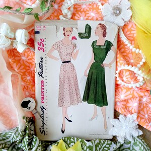 May include: A vintage Simplicity printed sewing pattern with illustrations of two dresses. The pattern is size 16, bust 34 inches, and priced at 35c. The dresses are a pink polka dot dress and a green dress. Floral fabric and decorative elements are in the background.