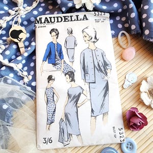 Op de afbeelding: Vintage naaipatroon "Maudella" met illustraties van een jasje en een jurk. Het patroon toont een vrouw in een blauw jasje en jurk, met een borstomvang van 91 cm. Het patroon staat op een lichtbeige achtergrond.