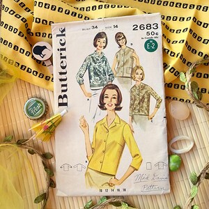 May include: Vintage Butterick sewing pattern, size 14, featuring illustrations of women's blouses and jackets. The pattern cover has a retro design with the number 2683 and the text "Mid Davis Pattern". The background includes yellow fabric and decorative items.
