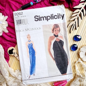 Könnte beinhalten: Ein Vintage-Simplicity-Schnittmuster mit einem Design von Jessica McClintock. Das Muster zeigt ein Abendkleid im Halter-Stil in Blau und Schwarz. Das Cover ist weiß mit schwarzem Text und einem Barcode.