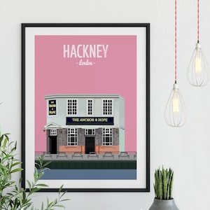 May include: A pink and white illustrated print of a pub called "The Anchor & Hope" in Hackney, London. The pub has a white facade with black windows and a blue sign.