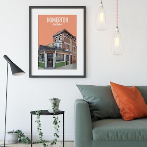 May include: A black framed print with a peach background and a white illustration of a building with the text "HOMERTON - East London -" at the top.
