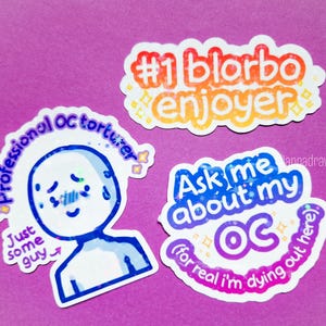 Puede incluir: Tres pegatinas coloridas sobre un fondo morado. Una pegatina dice "#1 blorbo enjoyer" en naranja y amarillo. Otra dice "Professional OC torturer" con una figura de dibujos animados triste. La tercera dice "Ask me about my OC".