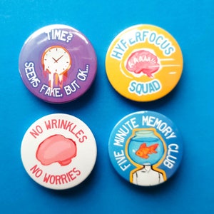 Peut inclure: Quatre badges ronds avec des motifs et des textes colorés. Le premier badge est violet avec une horloge qui fond et le texte "TIME? SEEMS FAKE, BUT OK..." Le deuxième badge est jaune avec un cerveau rose et le texte "HYPERFOCOUS SQUAD" Le troisième badge est blanc avec un cerveau rose et le texte "NO WRINKLES NO WORRIES" Le quatrième badge est bleu avec un bocal à poissons et le texte "FIVE MINUTE MEMORY CLUB"