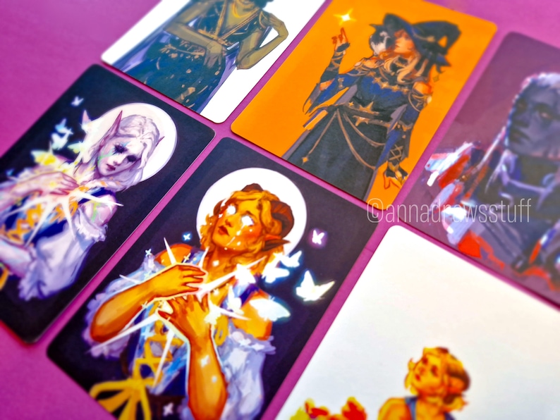Puede incluir: Seis cartas ilustradas con personajes de fantas&iacute;a. Las cartas est&aacute;n impresas sobre un fondo blanco con un borde morado. Los personajes son una mujer con el pelo largo y blanco, una mujer con el pelo largo y rubio, una mujer con el pelo largo y negro, una mujer con el pelo largo y marr&oacute;n, y una mujer con el pelo corto y marr&oacute;n. Las cartas son de diferentes tama&ntilde;os y formas.