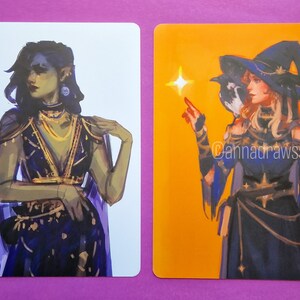 Puede incluir: Dos ilustraciones de mujeres con atuendos de fantas&iacute;a. La primera ilustraci&oacute;n es de una mujer con cabello azul oscuro y un vestido morado y dorado. La segunda ilustraci&oacute;n es de una mujer con cabello rubio que lleva un vestido azul y dorado y un sombrero de bruja. El texto "@annadrawsstuff" est&aacute; en la esquina inferior derecha de la segunda ilustraci&oacute;n.
