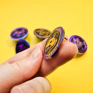 Op de afbeelding: Een regenboogkleurige, iriserende emaille pin met een zwart-witte illustratie van een hondenkop. De pin heeft de tekst "The Goodest Boy" rond de rand.