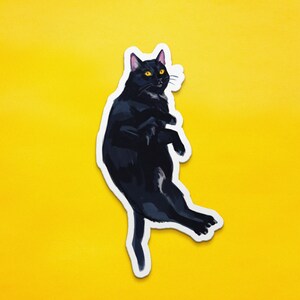 May include: A black cat sticker with yellow eyes, the cat is curled up in a ball with its paws tucked in.