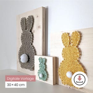 Könnte beinhalten: Drei Wandbilder aus Holz mit Hasenmotiven aus Fadengrafik. Die Hasen sind in Grau, Gelb und Grün gehalten und haben flauschige weiße Baumwollschwänze. Das größte Stück misst 30 x 40 cm.