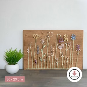Könnte beinhalten: Ein Wandbild aus Holz mit Blumendesign aus Faden. Das Kunstwerk zeigt verschiedene Blumen in Gelb, Lila, Blau und Weiß, mit grünen Stielen, vor einem braunen Holzgrund. Die Maße betragen 30 x 20 cm.
