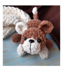 May include: A brown and white crocheted dog toy with black eyes and a black nose.