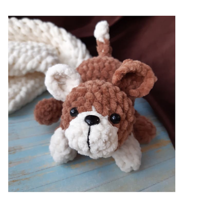 May include: A brown and white crocheted dog toy with black eyes and a black nose.