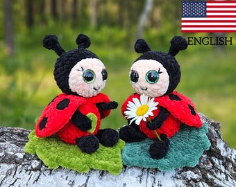May include: Two crocheted ladybug plush toys sitting on a green leaf. The ladybugs have black heads, red bodies with black spots, and large, sparkly eyes. One ladybug is holding a white daisy.