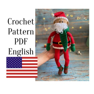 May include: Crochet pattern PDF in English for a red and white Santa Claus doll with a green scarf and hat. The doll is holding a green mitten in each hand.