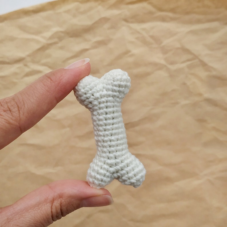 May include: A white crocheted dog bone toy.