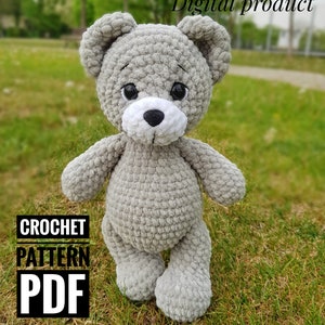 以下が含まれることがあります： グレーのぬいぐるみテディベアを作るためのクロシェパターンPDF。クマは黒い目と白い鼻をしています。