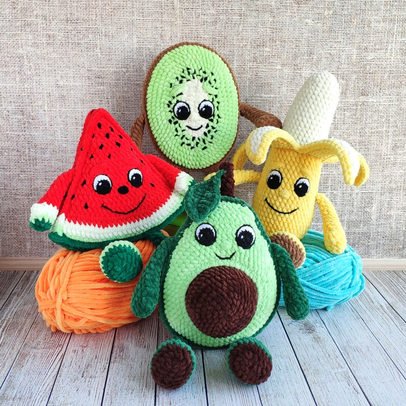 K&ouml;nnte beinhalten: Vier geh&auml;kelte Pl&uuml;schtiere in Form von Wassermelone, Avocado, Kiwi und Banane. Die Spielzeuge haben l&auml;chelnde Gesichter und sind aus weichem, farbenfrohem Garn gefertigt.