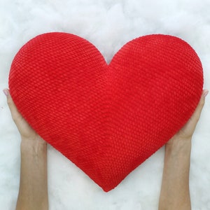 May include: A large red heart-shaped pillow with a textured surface.