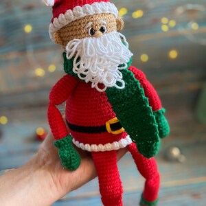 May include: Crocheted Santa Claus doll with a red hat, white beard, green scarf, and red and white striped socks.