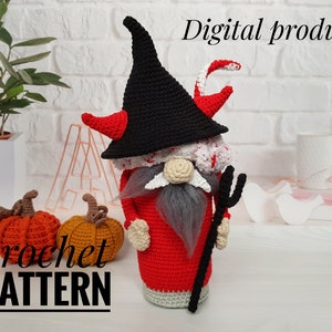 May include: A handmade crochet gnome in a devil costume, featuring a black hat with red horns, a red robe, and a gray beard. The gnome holds a black trident. The image also includes two crochet pumpkins and the text "crochet PATTERN".