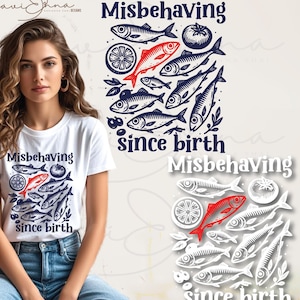 May include: White t-shirt with a graphic design featuring fish, a tomato, and a lemon slice. The text "Misbehaving since birth" is above and below the illustration. The design is in navy blue and red.