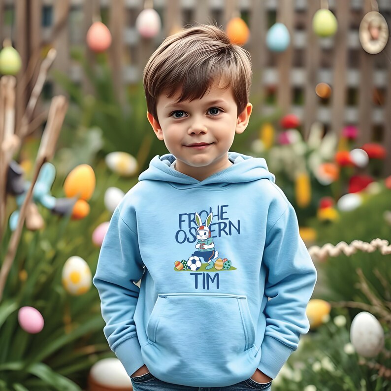May include: A light blue hooded sweatshirt with a graphic of a bunny rabbit playing soccer and the text "Frohe Ostern Tim".