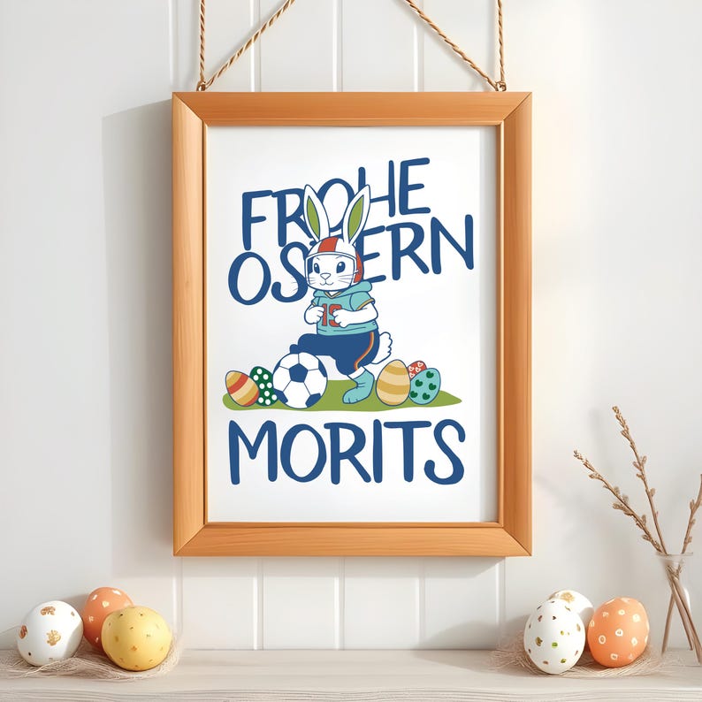 May include: A framed print with a white bunny wearing a helmet and holding a soccer ball. The text on the print reads "Frohe Ostern Morits".