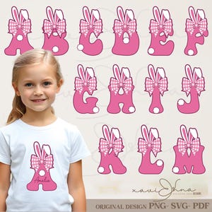 May include: Pink alphabet letters with bunny ears and gingham bows, themed for Easter. A young girl wears a white t-shirt with the letter "A" and the name "Amelia" printed on it. The design includes a bunny ear and bow graphic.