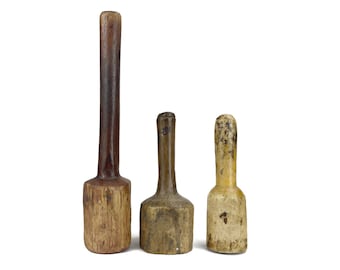 May include: Three antique wooden mallets of varying sizes. The largest has a long, dark brown handle and a light brown head. The middle mallet is shorter with a light brown head and handle. The smallest is off-white with a light brown handle.