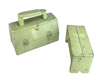 May include: A vintage, light green wooden toolbox with a handle and a small matching step stool. The toolbox has metal hinges and a clasp. The paint is distressed, giving it a rustic appearance. The step stool is rectangular with angled legs.