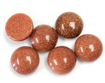 May include: Six polished, round, reddish-brown gemstones with a sparkling, glittery appearance. One is flat, while the others are spherical. The gems are arranged on a white background, showcasing their reflective surfaces.