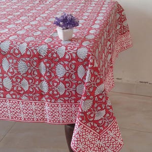 May include: A red and white floral tablecloth with a white border. The tablecloth is made of cotton and has a traditional Indian design.