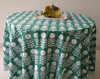 Può includere: Una tovaglia rotonda verde con un motivo floreale bianco. La tovaglia ha un bordo a strisce bianche e verdi. Un mazzo di banane è su un piatto bianco sulla tovaglia.