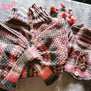 May include: A pink and brown crocheted sweater and vest set for a small dog. The sweater has a high collar and buttons down the front. The vest has a lace-up detail in the front. The text "DOGCLOTHES made with LOVE" is visible in the image.