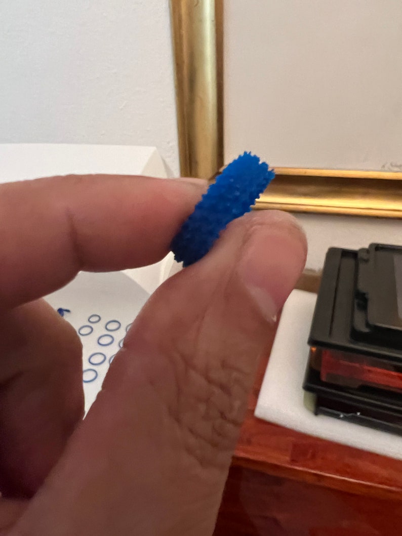May include: A blue rubber ring with a textured surface. The ring is designed to help with grip and dexterity.