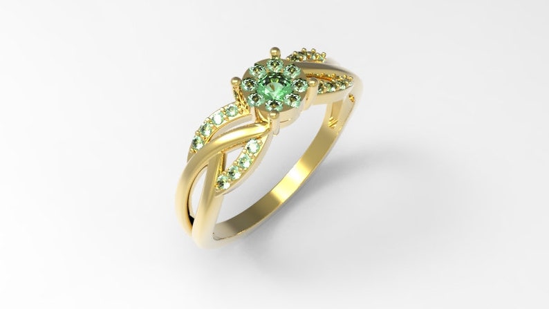May include: A gold ring with a green gemstone surrounded by smaller green gemstones. The ring has a twisted band design.