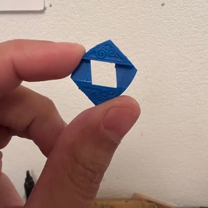 May include: A blue plastic diamond-shaped frame with a square opening in the center. The frame has a decorative design around the edges.
