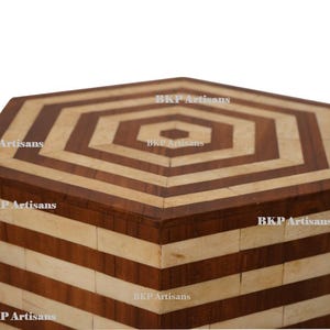 May include: Hexagon shaped wooden box with a geometric pattern of brown and beige stripes. The box is made of wood and has a natural finish.